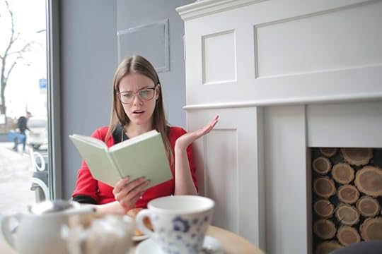A woman reading book with a surprised expression.,