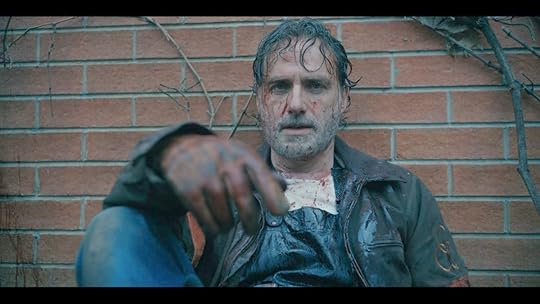 Rick Grimes sits against a wall with his right hand visible and blood on his face in the ones who live walking dead spinoff