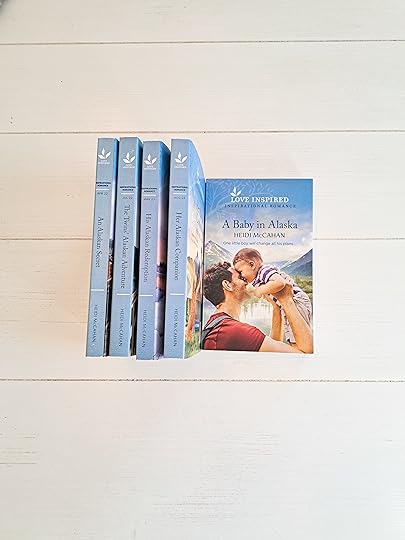 5 Love Inspired paperback novels from the Home to Hearts Bay series lined up with spines out on a white shiplap table.