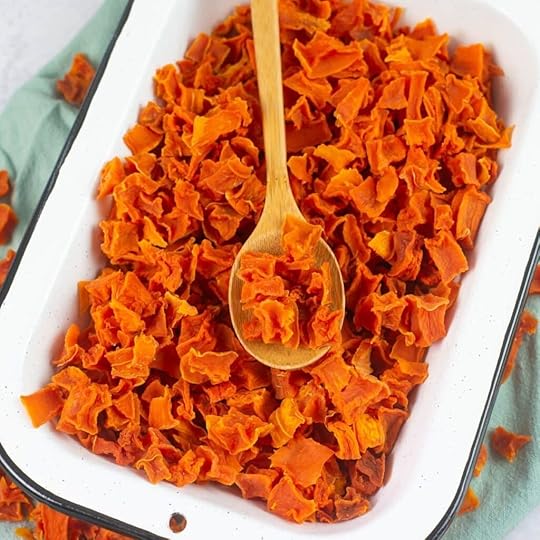 Cubed dehydrated butternut squash in an enamel bowl with a wooden spoon.