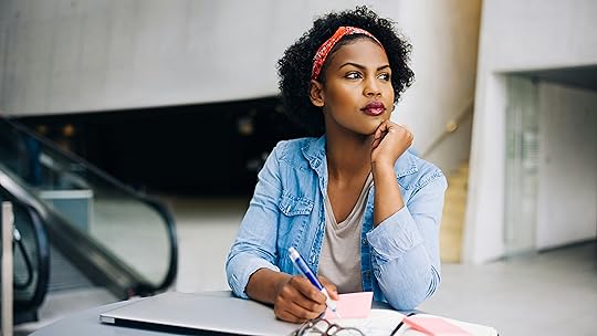 Lady is deep in thought while working at a table in a modern office building lobby