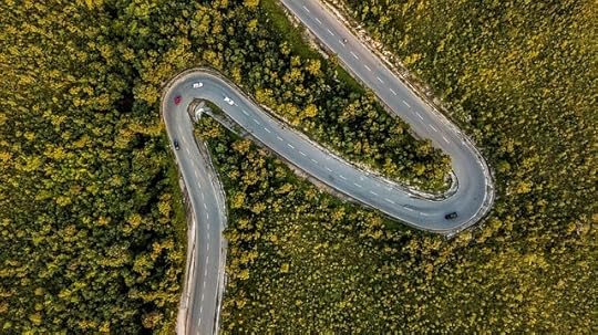 An arial view of a meandering paved road through green trees