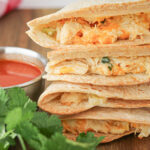 side view of buffalo chicken quesadillas with filling coming out of sides.