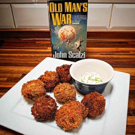 Old Man's War by John Scalzi in front of a plate of breaded mushroom balls with a cup that has some white substance and chives in it.