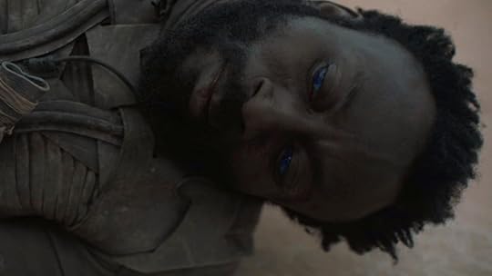 A man with a beard and blue eyes lies dead in the sand in Dune