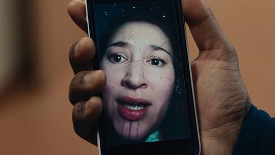 A hand holds a cellphone showing a scared woman on True Detective: Night Country