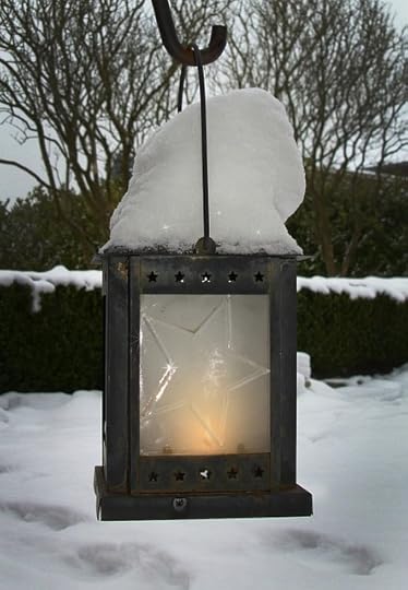 Iron lantern with star etching hanging in a snow-covered yard