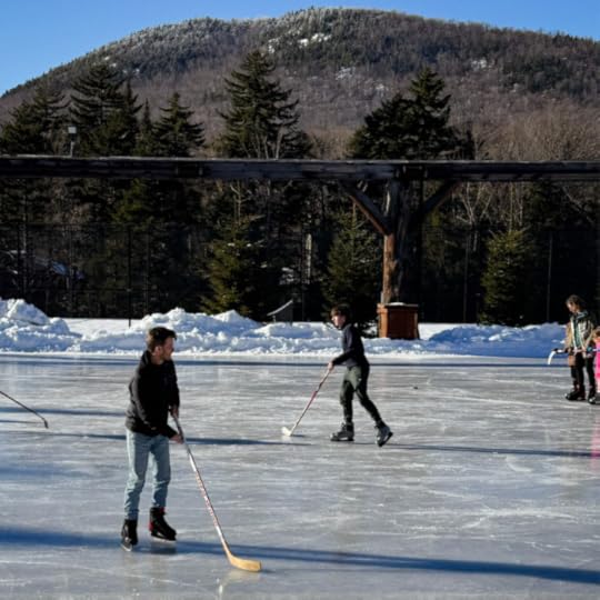 two guys ice skating on a lake in front of mountains