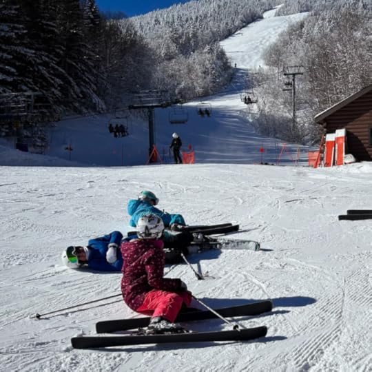 snowboarders resting in the snow at the bottom of mountain