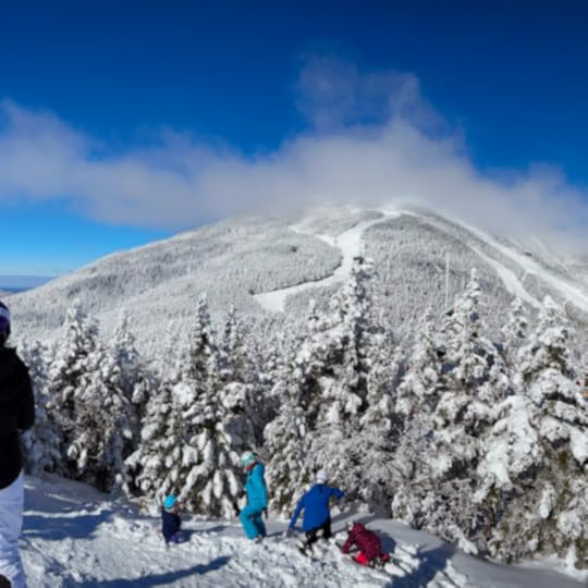 snowboarders in the distance with a mountain in front of them