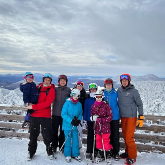 group of snowboarders pose with a snowy valley stretching behind them