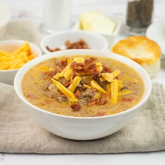 A bowl of Crock Pot Cheeseburger Soup topped with crumbled bacon and shredded cheese.