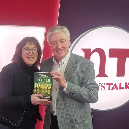 A man and a women holding a book smiling at the camera