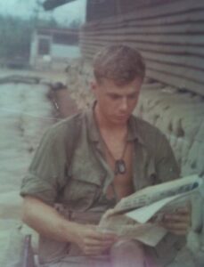 U.S. soldier reading a newspaper next to a building surrounded by sandbags
