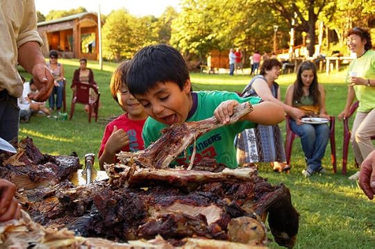 The Chilean inspiration in my romance books: Child playfully trying to take a bit out of a big piece of bbq meat.