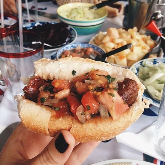 The Chilean inspiration in my romance books: Piece of marraqueta with longaniza (sausage), and pebre. Different types of salad show in the background: potato, beets, corn, and others.