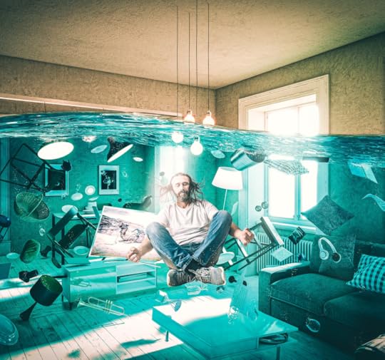 A hippy looking man listening to earbuds floats cross legged as his living rooming room fills with blue water