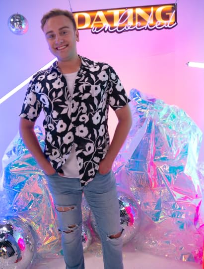 A man smiling to camera while standing with his hands in his pockets