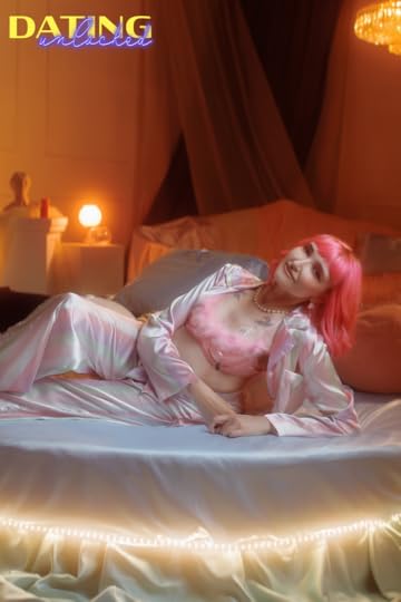A woman with pink hair lounges seductively in a boudoir style photo