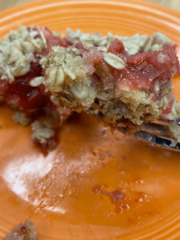 orange plate with Strawberry Rhubarb Bars on a fork