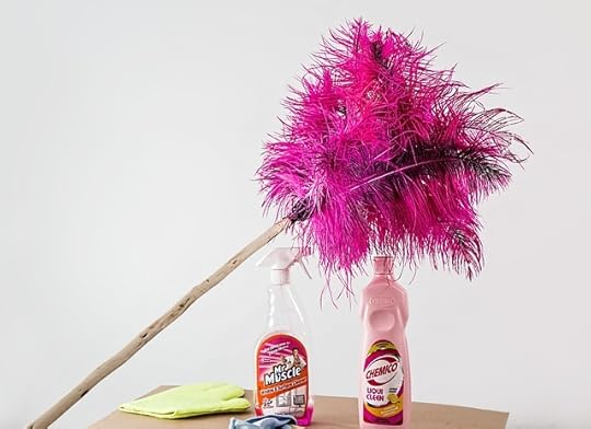 Pink feather duster leaning on top of bottles of cleaning products