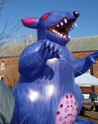 Large blue inflatable rat with claws and teeth and pink eyes outside MASSMoCA