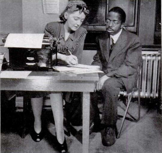 Photo from of Frances Sweeney at her desk taking notes from a fellow black editor, William Harrison, sitting beside her.