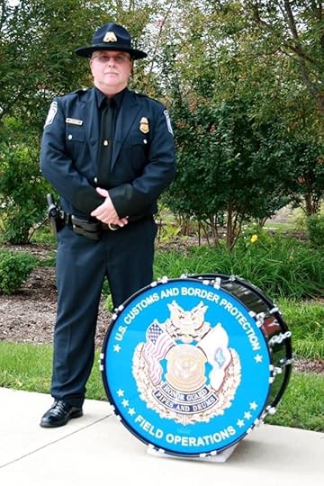 Man wearing a U.S. Customs and Border Protection uniform standing next to a bass drum