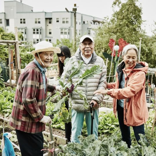 A group of older Asian people stand proudly in their community garden