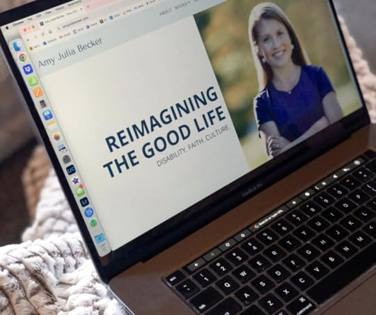 photo of a laptop on on top of a blanket. The home page of Amy Julia's website is on the screen, which has the logo 