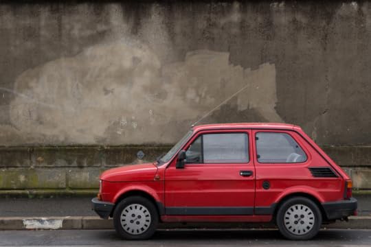 A very small red car parked along a curb.