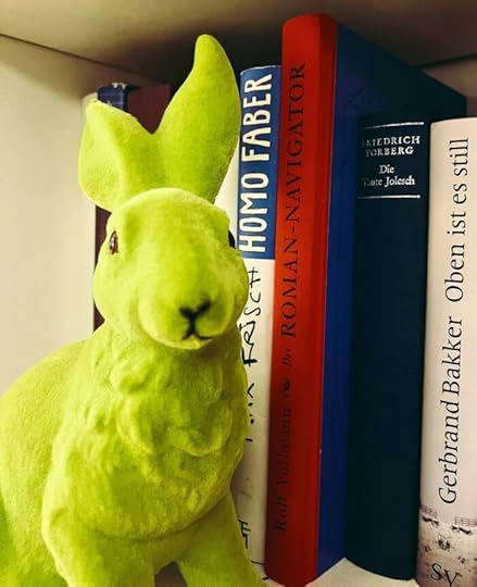 Ein grüner Dekohase vor Büchern in einem Regal