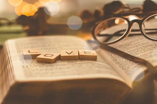 An open Bible with the word love spelled in tiles.