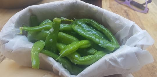 A bunch of green string beans inside a white paper shaped like flat bread