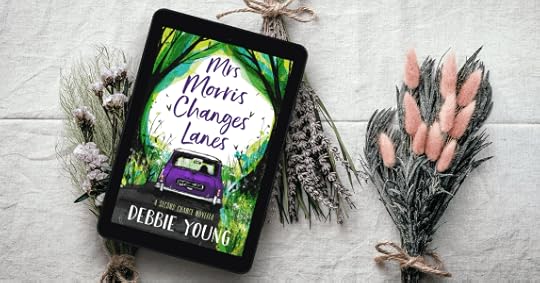 Cover of Mrs Morris Changes Lanes viewed on a tablet, with bunches of spring flowers alongside