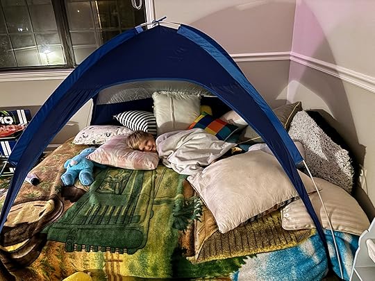 a child sleeping on a bed with a tent