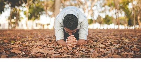 a man praying on his knees in the woods