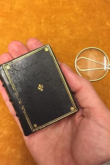 A tiny book held on the fingers of an open hand