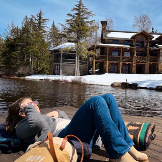 Amy Julie lays on her back on a dock and looks up at the sky. She is wearing eclipse glasses