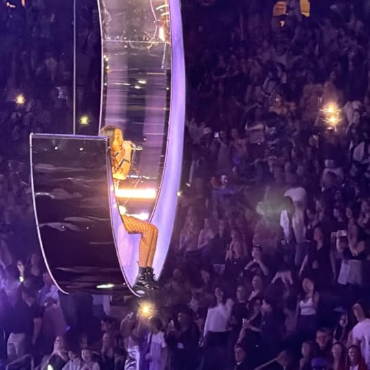 Olivia Rodrigo in concert floating on a giant moon above the crowd