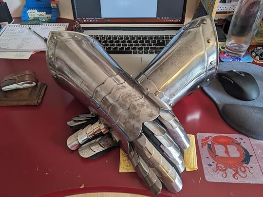 A pair of armoured gauntlets, crossed on a desktop.