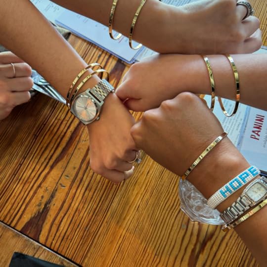 gold friendship bracelets on the arms for four women