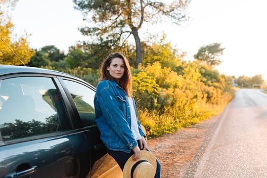 Girl with a hat in her hands near a car on the road