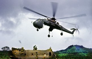 A badly damaged Chinook (on the ground) is recovered by a First Air Cav CH-53 Flying Crane. The Chinook was repaired and returned to service. Photo courtesy of the author.