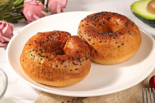 A pair of everything bagels on a white plate.
