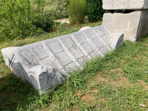 A stone sarcophagus lid, carved to look like a tiled roof.