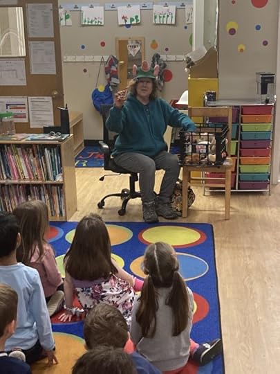 Back of students' heads. Watching Jane wearing pig hat and holding wooden spoon.