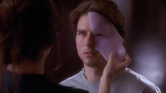 Penelope Cruz holds a piece of a mask up to Tom Cruise's face in