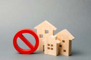 Wooden block homes with a ban sign | Andrii Yalanskyi/Dreamstime.com