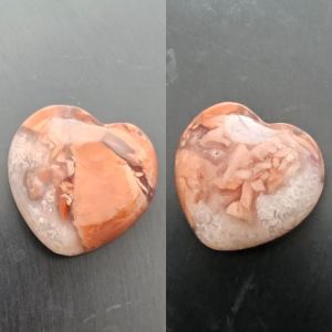 picture of a heart shaped polished piece of quartz, with inclusions that makes it look like salmon flakes in jelley.
